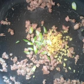 肉变色后加入葱姜末爆香。