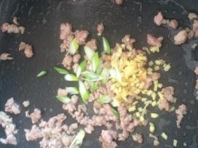肉变色后加入葱姜末爆香。