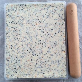 放入牛轧糖整形盒中，垫一张油纸，用擀面杖擀平整，压瓷实。