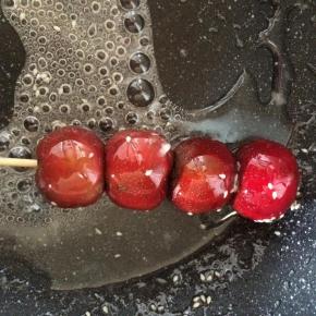 把串好的山楂串迅速裹上糖浆，放到不粘烤盘上自然冷却即可。