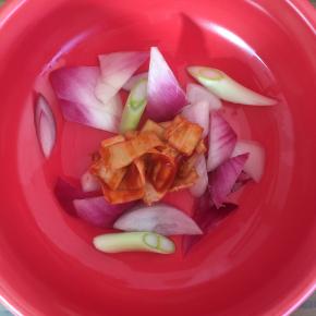 先将洋葱、葱、辣白菜铺在锅底。