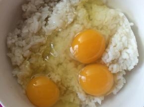 鸡蛋磕入米饭中。
