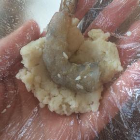 用一小块保鲜膜，取适量土豆泥，包裹上虾仁，露出虾尾部分。