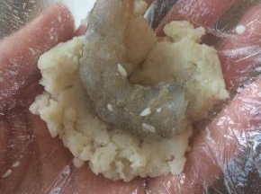 用一小块保鲜膜，取适量土豆泥，包裹上虾仁，露出虾尾部分。