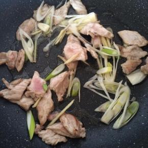 肉片变色后放入葱姜爆香。