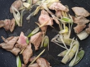 肉片变色后放入葱姜爆香。