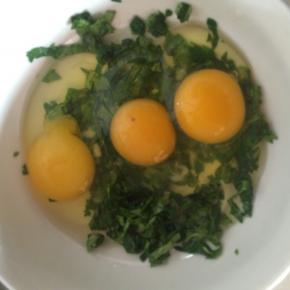 切碎的芹菜叶内磕入鸡蛋。