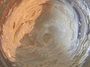 牛奶和白砂糖加热溶化放凉。黄油软化打发至白色，分多次加入糖水，打发至有光泽