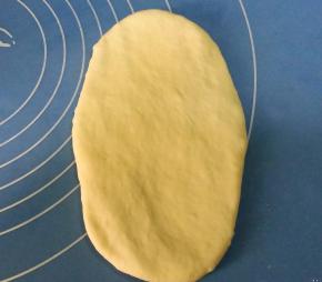 取松驰好的面团，用擀面杖从中间，向上下两端擀成椭圆形；