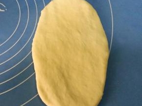 取松驰好的面团，用擀面杖从中间，向上下两端擀成椭圆形；