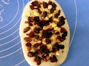 翻面，铺上适量的果料与坚果。由上至下卷起；