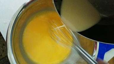 把放凉的面糊慢慢倒入鸡蛋牛奶液中，边倒边用手动打蛋器画圈圈，搅拌成可以流动的稀面糊状态，这时候预热烤箱，上下火175度