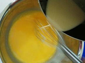 把放凉的面糊慢慢倒入鸡蛋牛奶液中，边倒边用手动打蛋器画圈圈，搅拌成可以流动的稀面糊状态，这时候预热烤箱，上下火175度
