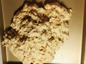 把糖挖出来放到金色烤盘里，这时候戴一次性手套，然后在黄油碗里抹点黄油防粘（倒黄油的速度快，碗里会有残留）用力搓揉牛轧糖，让花生分布更均匀，