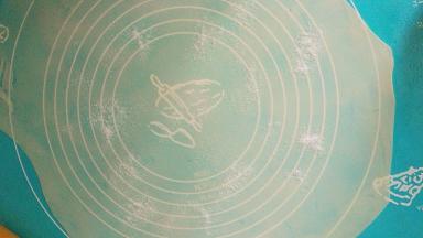 取一个面团，擀薄，面团下面有油，很容易擀薄，越薄越好吃，擀好的面饼上洒少许细砂糖