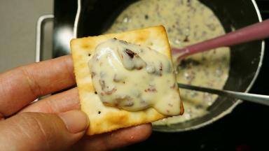 拿个勺子舀一勺牛轧糖放饼干上面，再拿一块饼干盖上