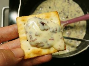 拿个勺子舀一勺牛轧糖放饼干上面，再拿一块饼干盖上
