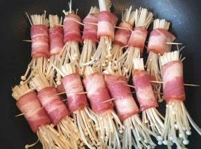 不沾平底锅预热，放入金针菇卷。不需要放油，培根在煎的过程中会出油