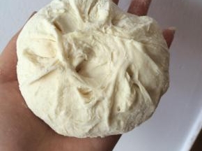 剂子揉圆，按扁，用擀面杖把边上擀薄一些，包上馅料，包成包子。