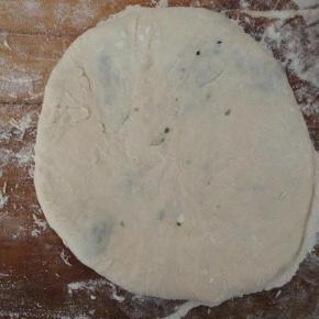 包子底朝上按扁，再轻轻的擀薄成圆形。