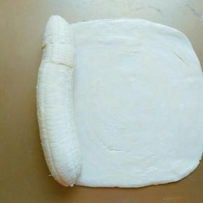 香蕉去皮，放在飞饼的一边(如果香蕉太弯，可以切几刀重新摆成稍直的形状)