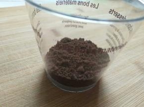 木糠杯的杯子用勺子放入一勺奥利奥碎，并用勺子整平，或者用擀面杖的头捣平