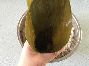 粽味卷成三角形，最下面要有一个折角，避免漏米