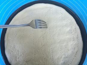 面团擀成圆形，放入披萨盘，用手推出边，叉子扎出小洞，防止烘烤时鼓起。