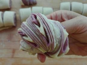 自上而下卷起来，切成均等剂子，两两摞在一起，借助筷子从中间深压一下，两手相反方向扭转，捏好收口
