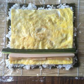 再铺上鸡蛋饼，放上黄瓜条、香肠条