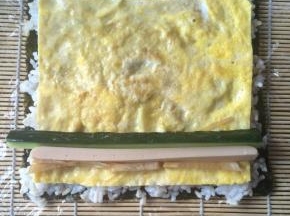 再铺上鸡蛋饼，放上黄瓜条、香肠条