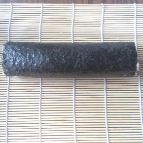 提起寿司帘的一端，慢慢卷起，边卷边压紧。