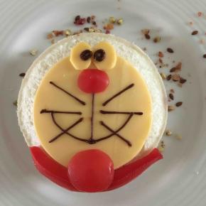 用番茄装饰鼻子和铃铛，用巧克力画出眼睛、嘴巴和胡子