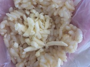 借助保鲜膜，一勺米饭中，包入适量芝士碎。