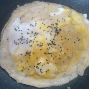 磕入鸡蛋，摊平抹匀。
鸡蛋半熟时撒少许黑芝麻。