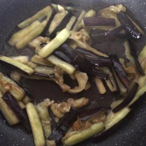 锅内倒入适量食用油，放入沥干水的茄子，翻炒1分钟，捞出沥油。