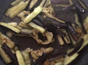 锅内倒入适量食用油，放入沥干水的茄子，翻炒1分钟，捞出沥油。