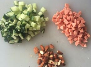 黄瓜切小丁、火腿肠切小丁、巴旦木用刀拍碎。