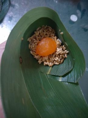 左手捏住，右手用勺子舀适量馅料放入，装6分满，用大拇指压实。加入蛋黄