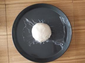 面团取出放披萨盘上盖上保鲜膜醒15分钟