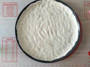 用手把面团在披萨盘上平铺开