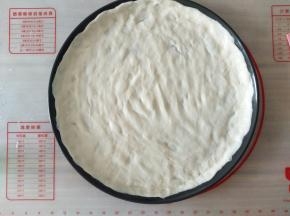 用手把面团在披萨盘上平铺开