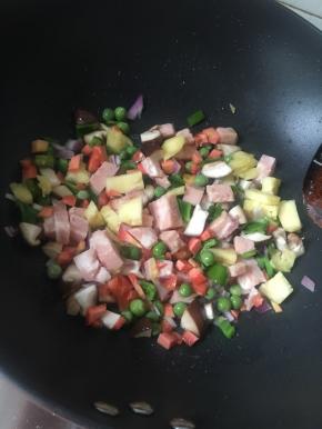 将油烧热后倒入青豆、胡萝卜、洋葱、香菇等炒一会儿，然后倒入其他食材炒出香味，再撒胡椒粉、倒入生抽继续翻炒均匀。