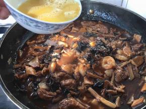 浓稠度以卤汁能挂在面上为好，这是勾完芡的样子，这时候改小火，碗里留少许水淀粉，把鸡蛋打散，用筷子挡往下流鸡蛋液的碗边，让鸡蛋液顺着筷子和碗边的空隙往下流，要转圈洒鸡蛋液，让蛋液均匀分散在锅里，这时要有点小耐心等待蛋液定型哦。不过这步可以略去，您也可以把鸡蛋提前炒好，撒在盛在盆里的卤上，这样的做法叫盖冒。亲们，出锅前别忘了淋入1小勺香油（麻油）哦。