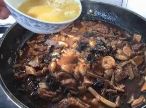 浓稠度以卤汁能挂在面上为好，这是勾完芡的样子，这时候改小火，碗里留少许水淀粉，把鸡蛋打散，用筷子挡往下流鸡蛋液的碗边，让鸡蛋液顺着筷子和碗边的空隙往下流，要转圈洒鸡蛋液，让蛋液均匀分散在锅里，这时要有点小耐心等待蛋液定型哦。不过这步可以略去，您也可以把鸡蛋提前炒好，撒在盛在盆里的卤上，这样的做法叫盖冒。亲们，出锅前别忘了淋入1小勺香油（麻油）哦。