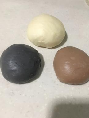 排气后将面团分成三部分，原色230克左右，另外两个150克左右，分别放入可可粉、竹炭粉揉均匀后，密封松弛15分钟左右。