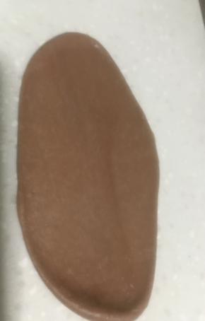 将咖啡色面团擀成鸭舌状。