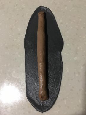 将咖啡色放入黑色面皮里、包裹起来搓成长条。