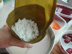 继续放糯米，长叶子一端朝下折压，按照三角形包起来即可