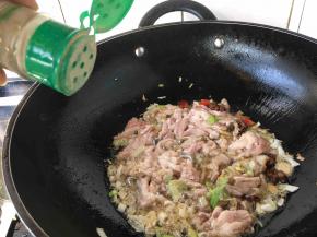 改中火，放入腌制好的肉片（别马上翻炒），当肉片稍稍变色定形型时放入1小勺白胡椒粉并翻炒，让肉均匀受热，再沿锅边倒入2勺料酒，翻炒几下。